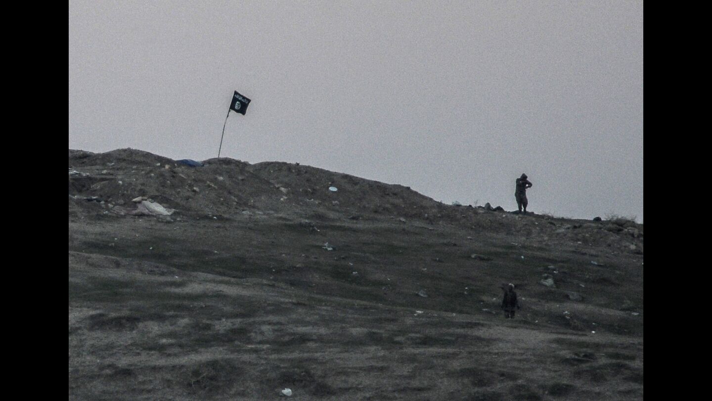 Islamic State militants patrol Oct. 23 near a flag they planted in Syria, just across the Turkish border.