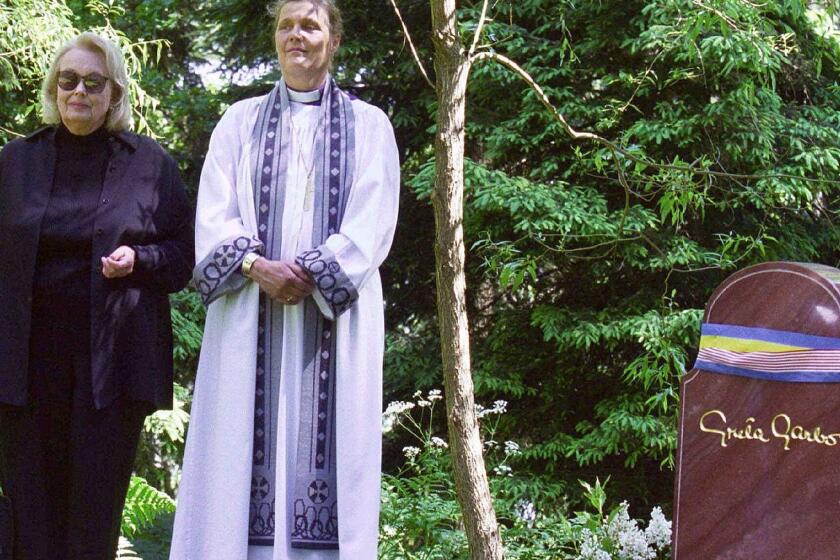 FILE - In this June 17, 1999 file photo, Gray Gustafson Reisfield, left, and Bishop Caroline Krook stand next to the tombstone of Greta Garbo after the memorial service at the Woodland Cemetery in Stockholm, Sweden. Reisfield, the sole heiress to her aunt Greta Garbo's estate and a woman who was a long-time companion to the late Swedish-born actress, has died, a family member said Monday, July 10, 2017. (Tobias Rostlund/TT via AP, File)