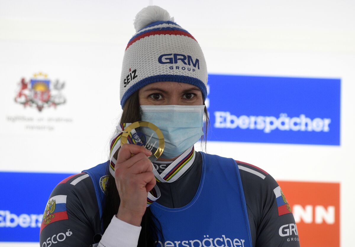 Tatyana Ivanova of Russia wearing a face mask to protect against coronavirus celebrates on the podium after finishing first of a women's race at the Luge World Cup event in Sigulda, Latvia, Sunday, Jan. 10, 2021. (AP Photo/Roman Koksarov)