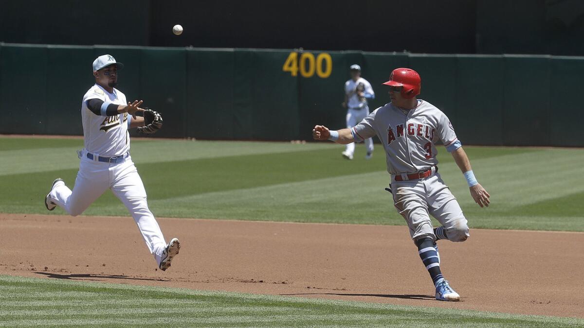 Oakland second baseman Franklin Barreto, left, throws to first base as the Angels' Ian Kinsler is caught in a rundown during the first inning.