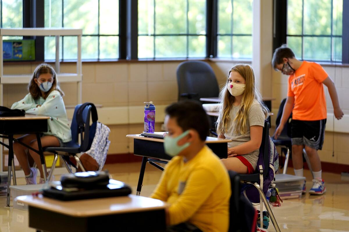 Estudiantes de quinto grado lucen máscaras en espera de su maestro en el aula en la Escuela Primaria Oak Terrace