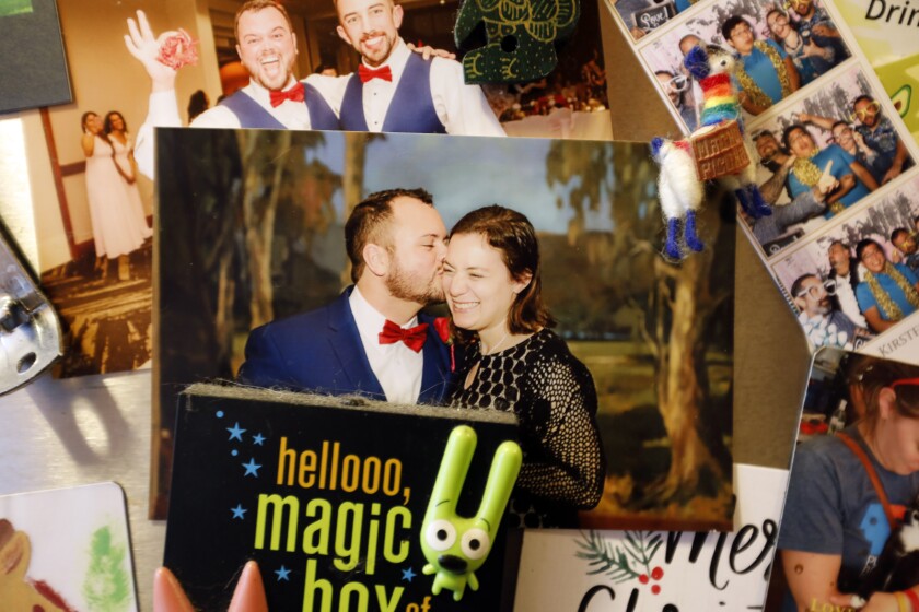 A photo of a man and woman kissing among many decorating a refrigerator door