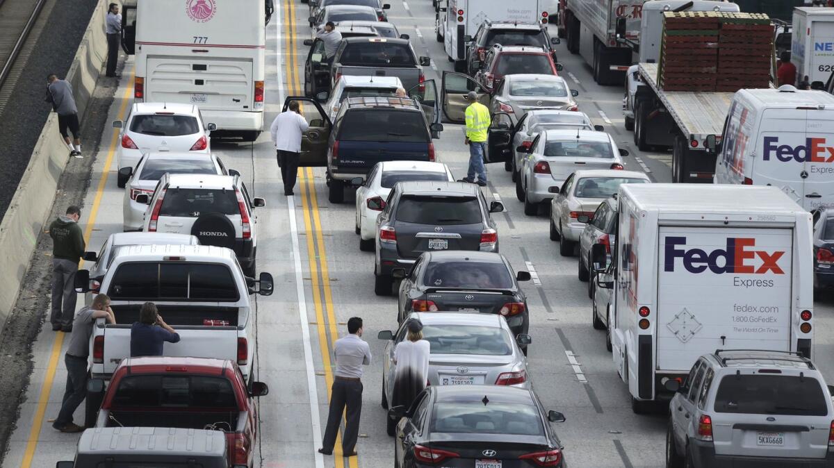 Motorists wait outside their vehicles in the backup after a suspicious device shut down traffic on the eastbound 210 Freeway in Pasadena for a couple of hours Wednesday morning.