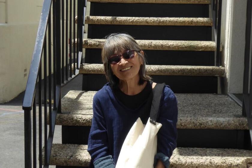 Eileen Saki wearing sunglasses and smiling while sitting on steps