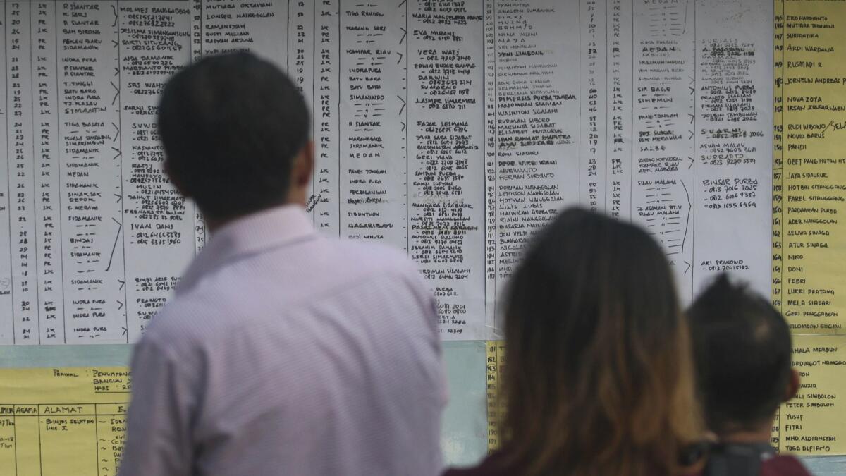 Relatives of the victims of a sunken ferry inspect the list of passengers.