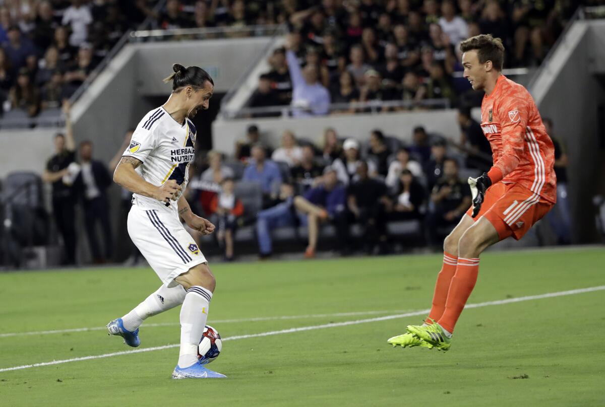 Los Angeles Galaxy's Zlatan Ibrahimovic, left, dribbles past Los Angeles FC goalkeeper Tyler Miller to score a goal during the first half of an MLS soccer match Sunday, Aug. 25, 2019, in Los Angeles. (AP Photo/Marcio Jose Sanchez)