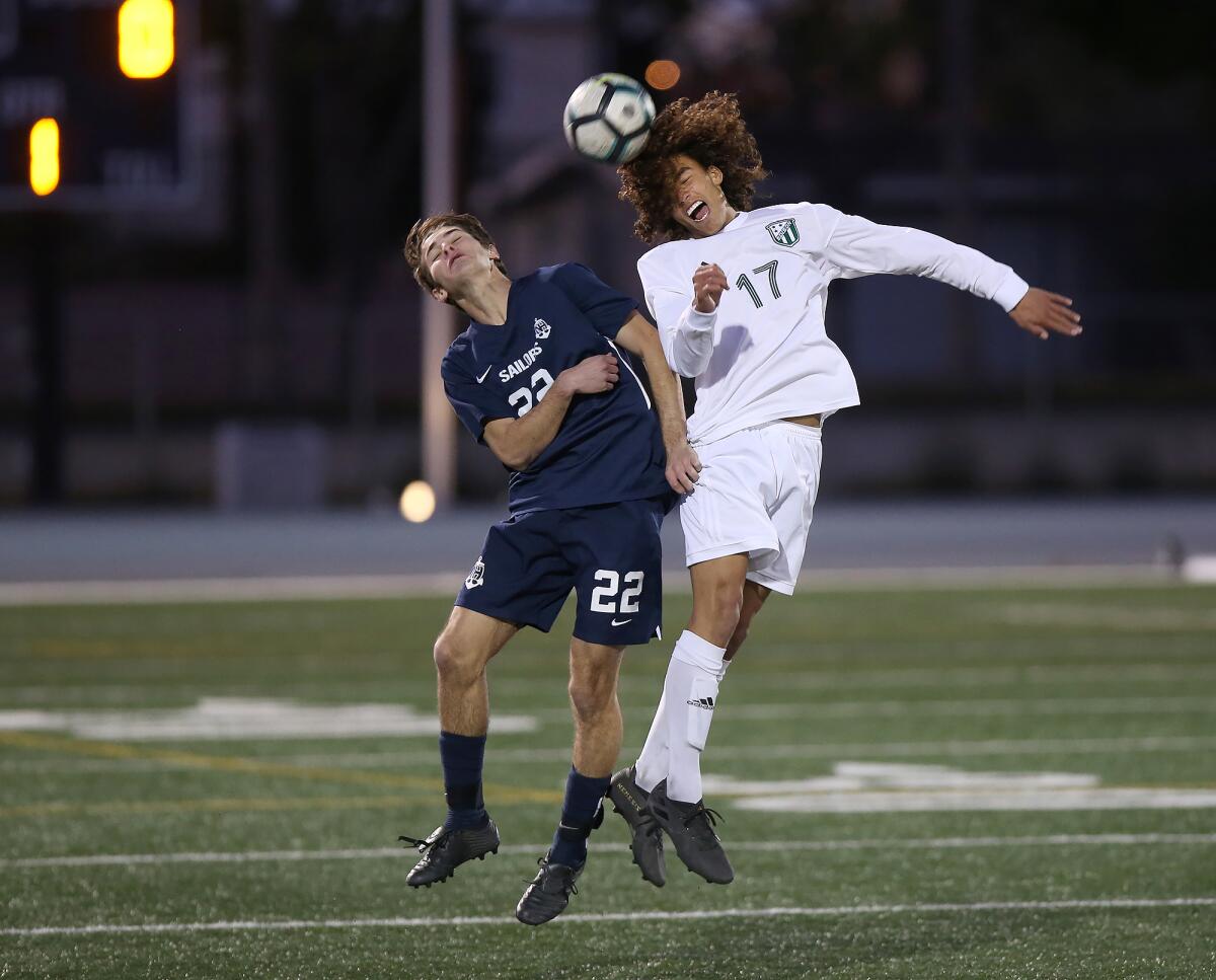 Edison’s Fin Roghair, right, uses his head to pass the ball up the field as Newport Harbor’s Ethan Federman bumps into him during a Surf League match on Wednesday.