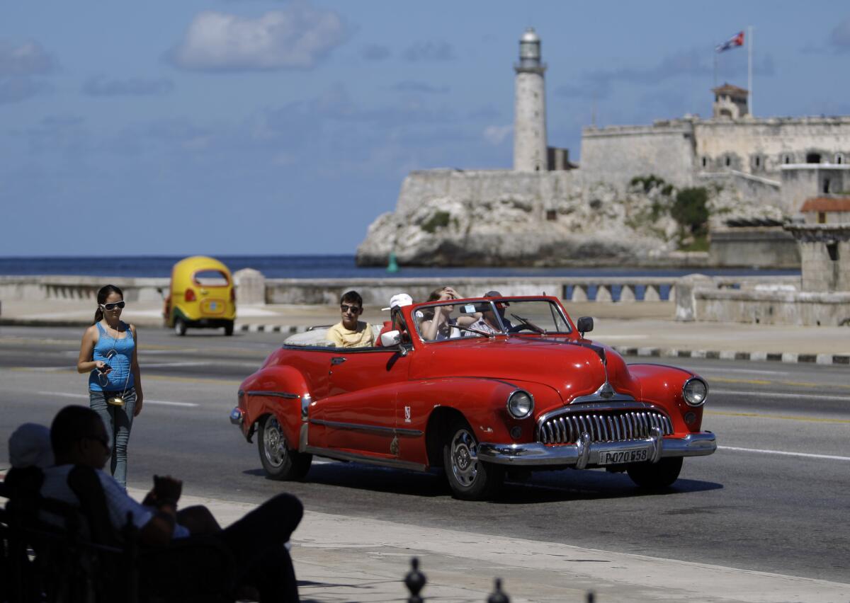 Tourists ride in a classic American car on the Malecon in Havana, Cuba.
