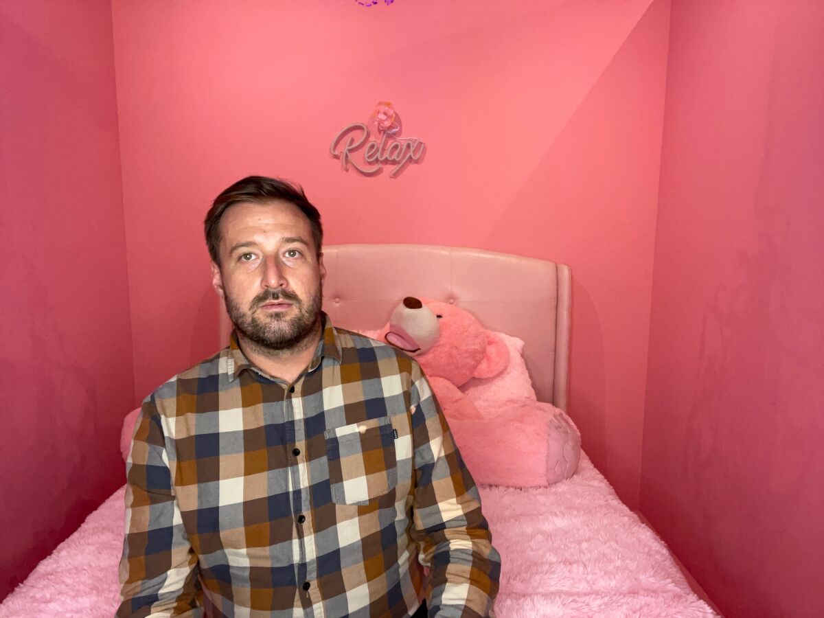 A man sitting on a bed in a pink room