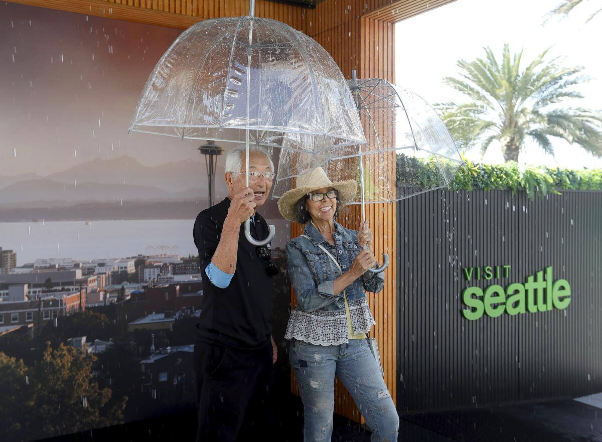 Sam Asaki and Alma O'Hamlon, from left, step into Seattle's traveling rain booth.