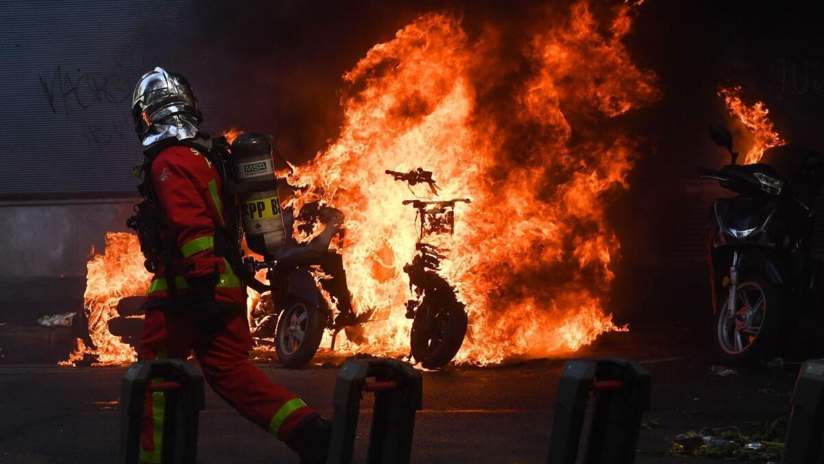 Firefighters extinguish scooters and motorbikes set ablaze during an anti-government demonstration by the "Yellow Vests" movement Saturday in Paris.
