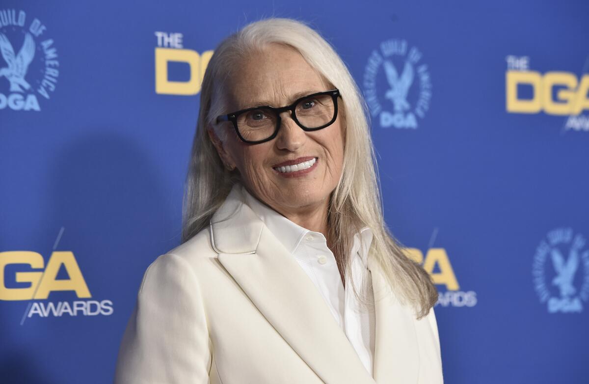 Jane Campion smiles in glasses and a white suit