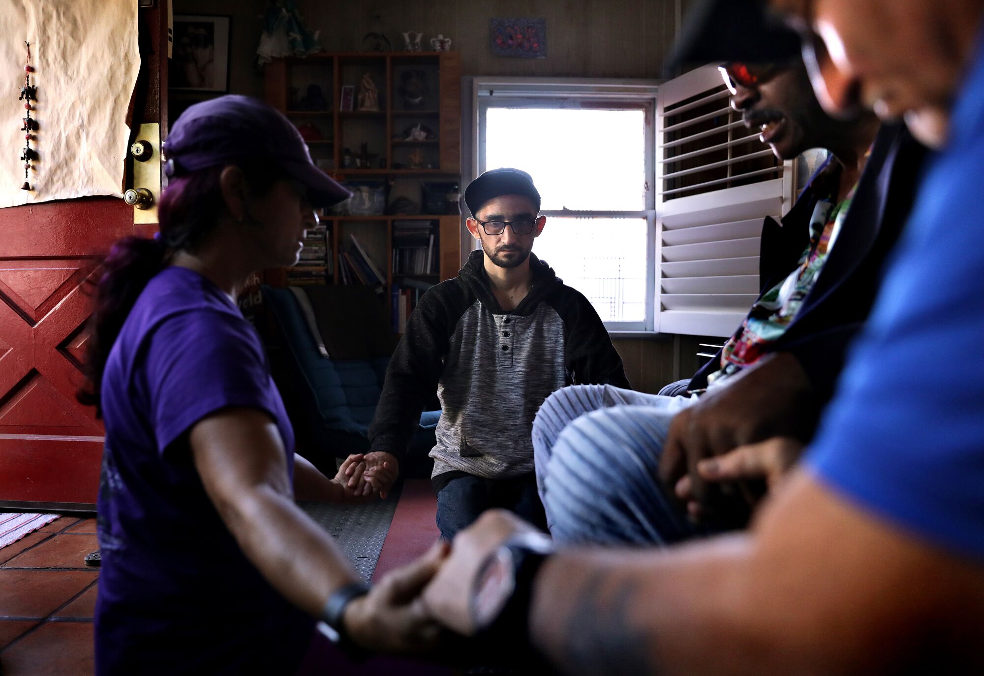 A group of people sit in a circle and holds hands 