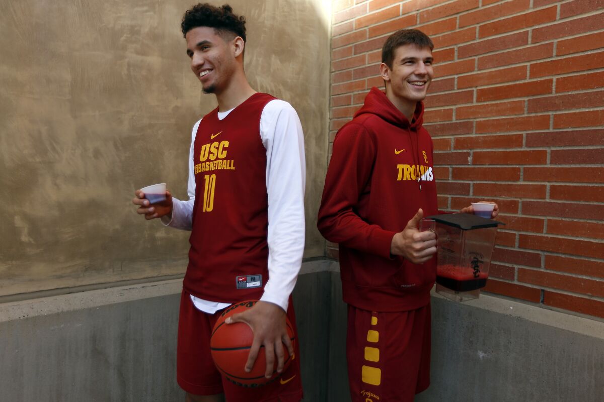 USC basketball players Bennie Boatwright, left, and Nikola Jovanovic, right, pose for a portrait holding beet juice, which they drink before every game.