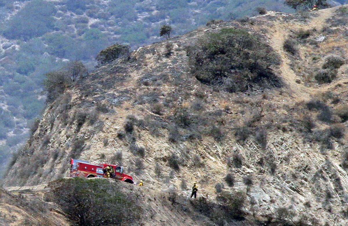 A fire crew in a burned out area of the Verdugo Mountains where the a brushfire, that started yesterday, continues to burn on Monday, June 23, 2014. The fire is above Brand Park, and hasn't threatened any structures.
