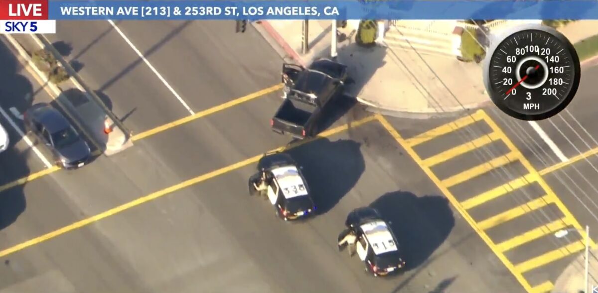Officers emerge from two police cars behind a truck in a city intersection.