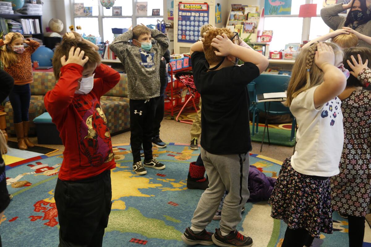 Second-graders hold their heads as they stand in class