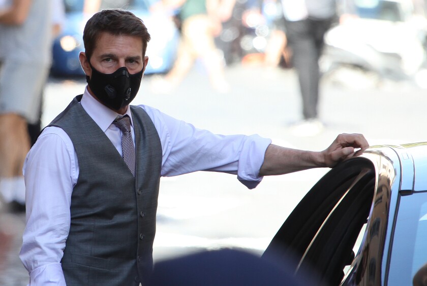 Tom Cruise wears a black face mask and gray vest