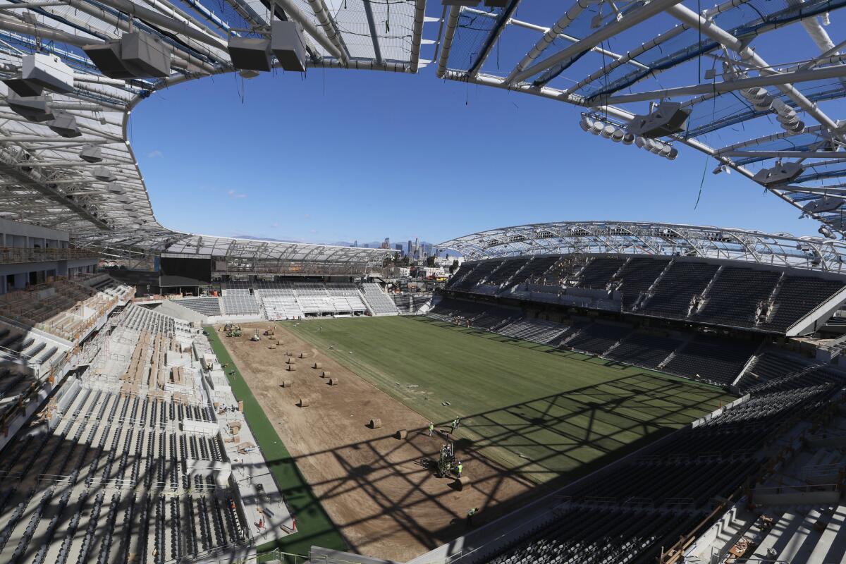 Workers install grass at LAFC's new Banc of California Stadium now under construction.