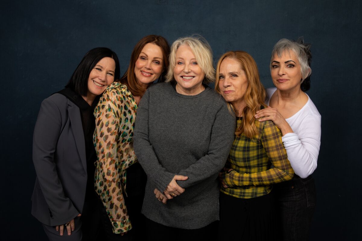 Five women lean into each other