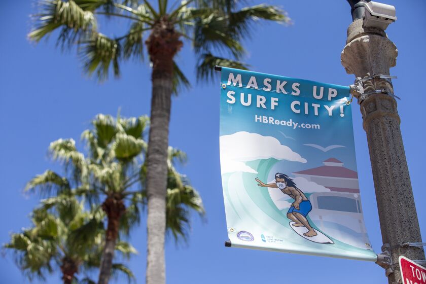 New sigs that say "Masks Up, Surf City" line Main St. in Huntington Beach on Tuesday, August 11.