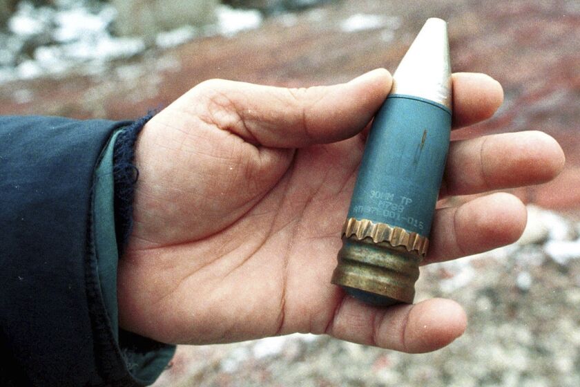 FILE - A member of a radiation team holds a 30mm armor-piercing shell containing depleted uranium, used by NATO during air strikes on Bosnia in 1995, which was found in a former military factory in the suburb of Vogosca, near Sarajevo, Jan. 15, 2001. (AP Photo/Hidajet Delic, File)