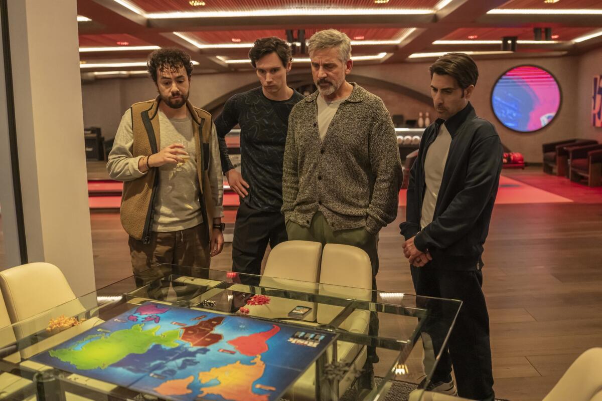 Four men stand around a table and look at a world map.