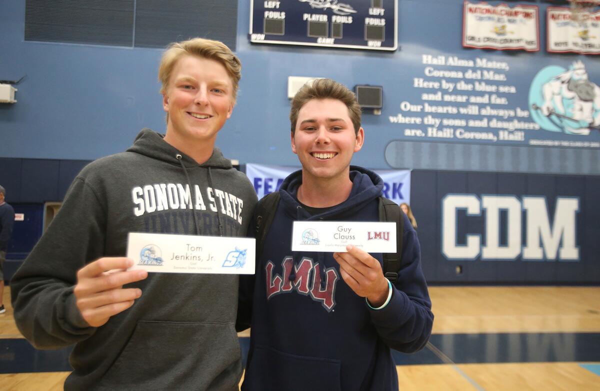 Golfers T.J. Jenkins, left, and Guy Clauss pose with their college choices, Jenkins (Sonoma State) and Clauss (Loyola Marymount University), during the Corona del Mar commitment ceremony in the main gym on Wednesday.
