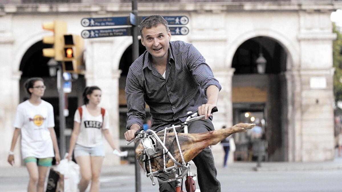 In an episode of the new series "I'll Have What Phil's Having," Phil Rosenthal rides around Barcelona with a jamón in his bicycle basket. The show will air locally on KOCE-TV.
