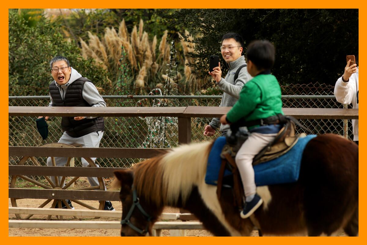 A child riding a pony while two adults smile and look on