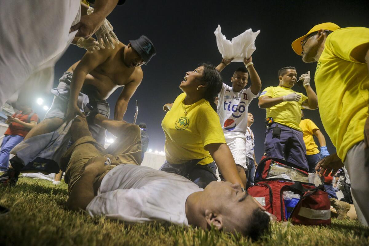 Aficionados al fútbol atienden en la cancha a los heridos por una estampida humana