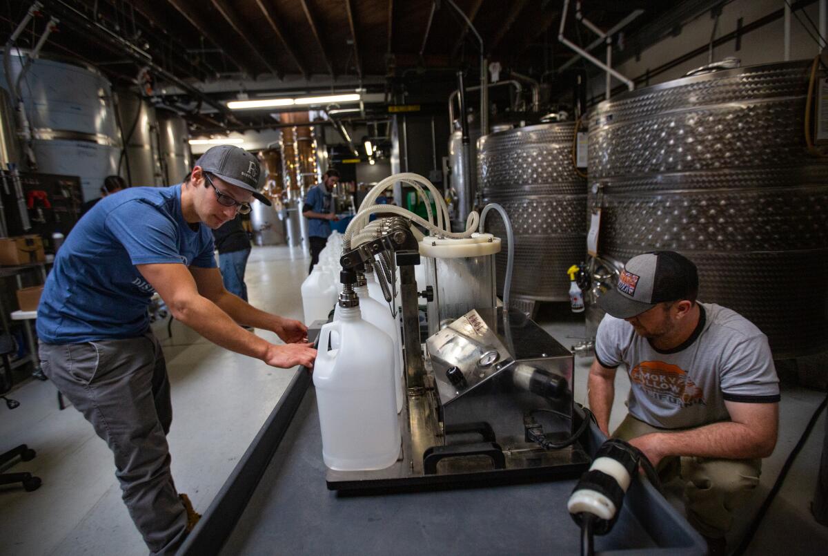 Workers at R6 DISTILLERY fill empty bottles with a batch of hand sanitizer made at the distillery during the pandemic