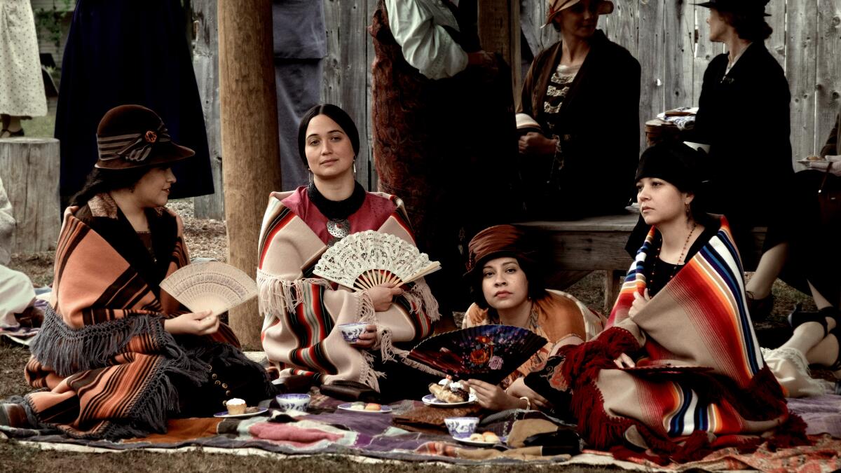 Osage women sit together and talk at a picnic in "Assassins of the Flower Moon."