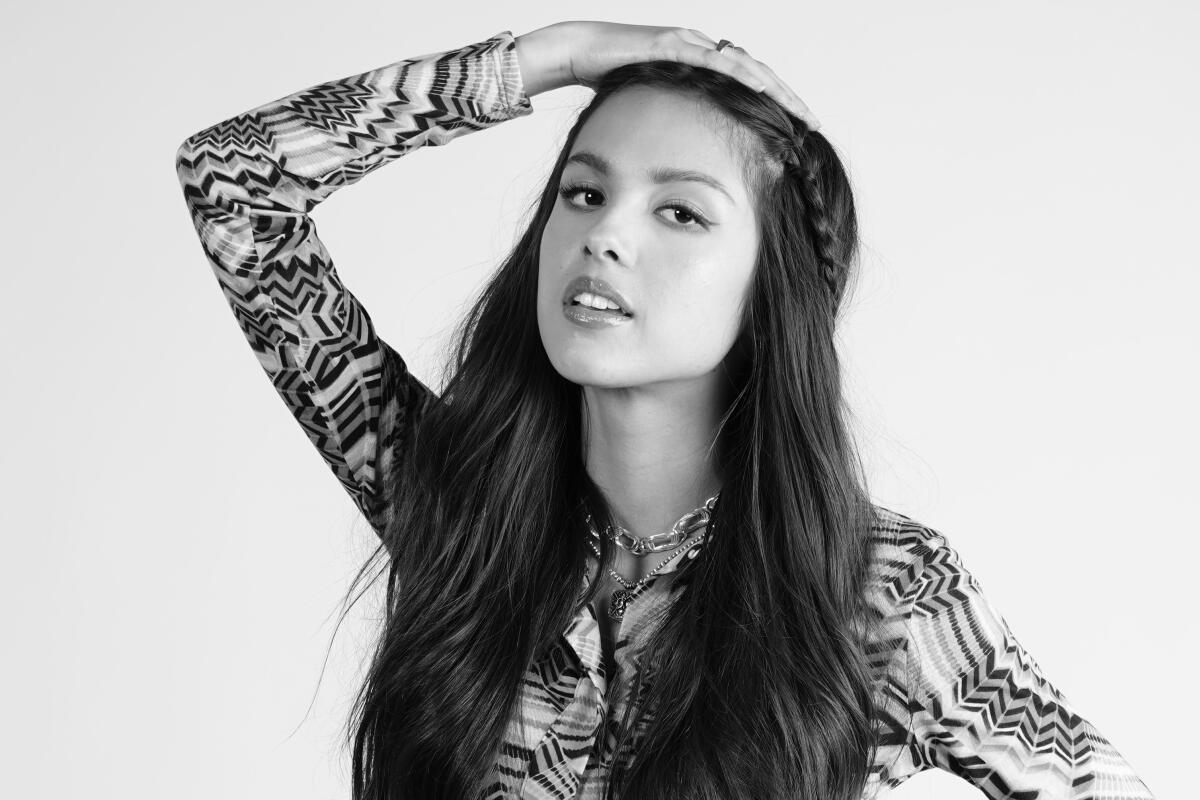 A black-and-white image of a woman posing with her hand on top of her head