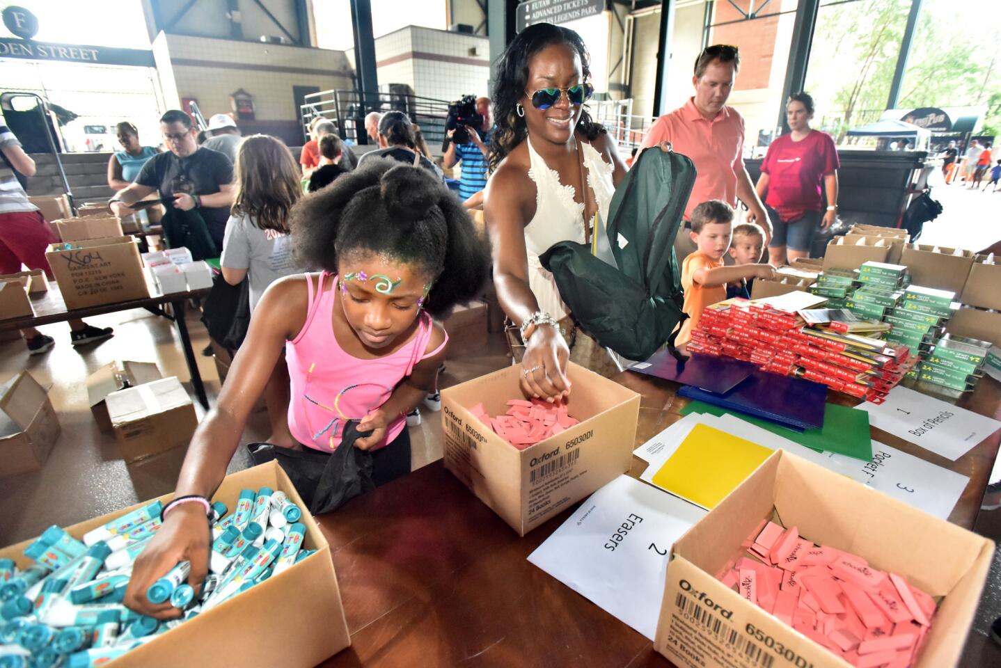 Lina Smith, 10, left, and her mother, Kenesha Smith of Owings Mills, a Bank of America employee, joined several hundred Bank of America volunteers who came with their families to Oriole Park at Camden Yards to pack 1,000 backpacks with school supplies for Baltimore City school students. The backpacks will be delivered to Armistead Gardens and Sandton-Winchester Achievement Academy on Monday.