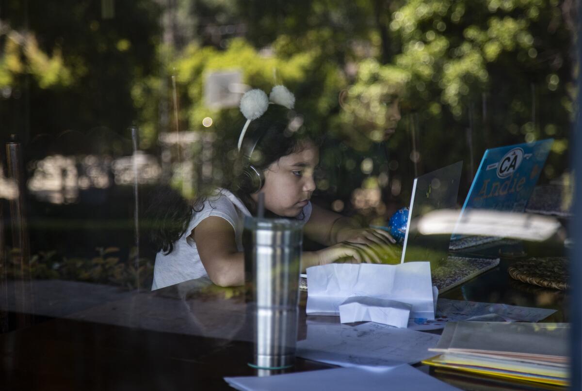 Rosie Roth, left, and Andie Bristow sit at a dining room table for typing class during home school in the midst of the coronavirus pandemic on April 21 in Riverside.