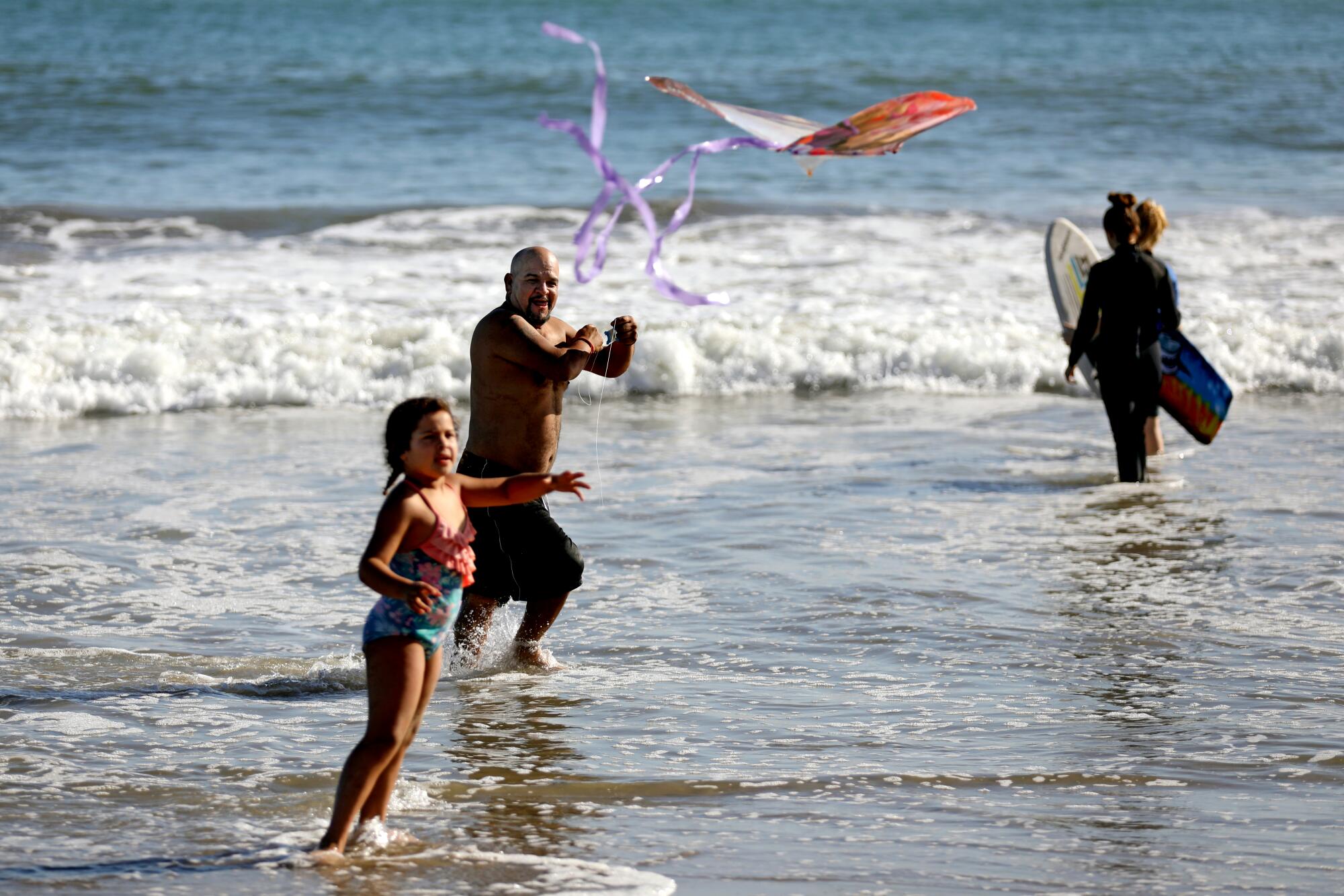 Beachgoers fly a kite at a Ventura beach.