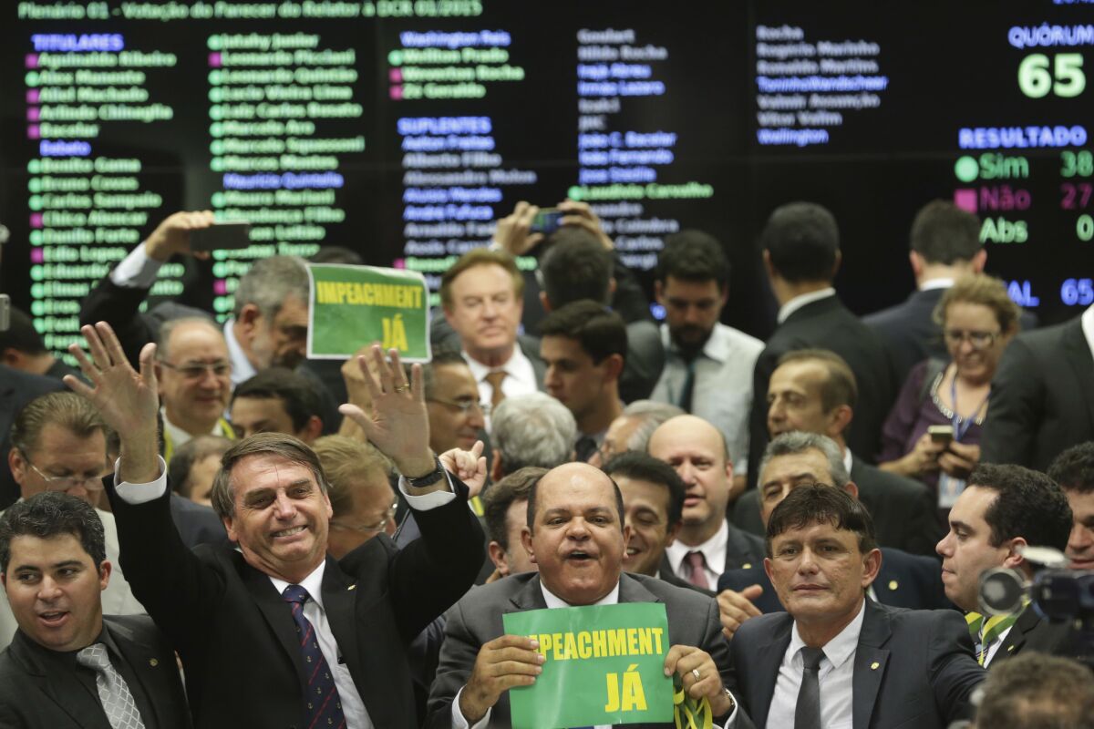 FILE - Then Congressman Jair Bolsonaro, seen holding his hands up, celebrates with other lawmakers after a committee voted on April 11, 2016, in Brasilia, Brazil, to advance impeachment legislation against President Dilma Rousseff. A week later during the impeachment vote in the lower Chamber of Deputies, Bolsonaro gave tribute to a colonel who oversaw the 1964-1985 dictatorship's investigative unit that tortured many Brazilians, including Rousseff. The significance of that vote is explored in the recently published Associated Press book, "Dilma's Downfall: The Impeachment of Brazil's First Woman President and the Pathway to Power for Jair Bolsonaro's Far-Right." (AP Photo/Eraldo Peres, File)