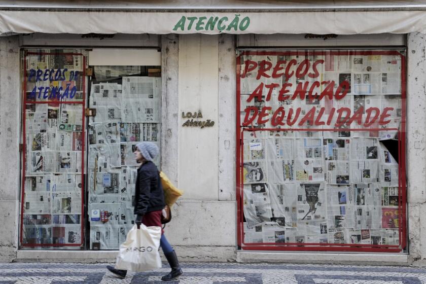 A Portuguese woman walks past a closed store on Fanqueiros Street in Lisbon.