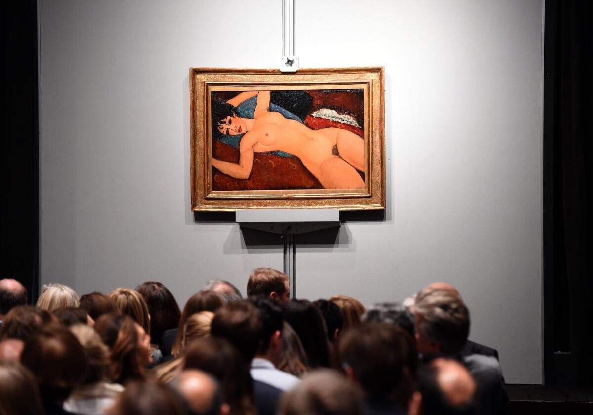 Crowds sit in front of Amedeo Modigliani's "Nu couche" during an auction at Christie's in New York. The painting sold for a whopping $170,405,000.