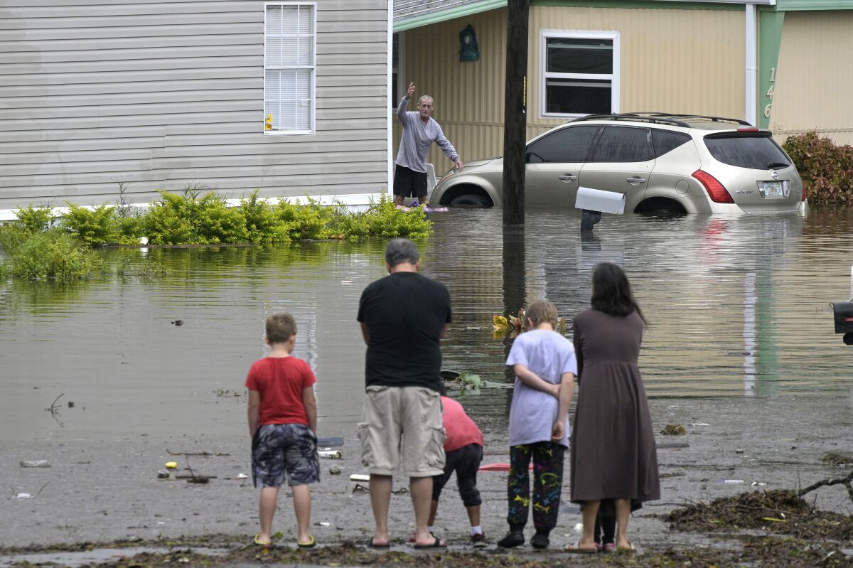 Residents check on one another in a flooded neighborhood in the aftermath of Hurricane Ian, Thursday, Sept. 29, 2022, in Orlando, Fla. (AP Photo/Phelan M. Ebenhack)