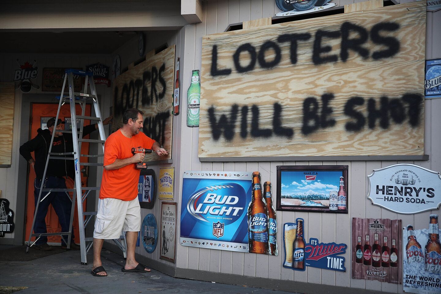 Doug Lewis, left, and Chris Williams cover the windows of Knuckleheads Bar and Grill in Myrtle Beach, S.C.