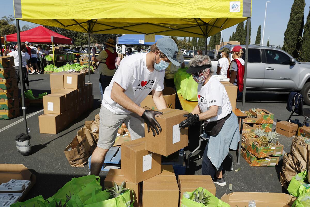 Volunteers Kyle Dornhofer, left, and Jackie Farr organize food packages for the drive-thru giveaway at IKEA.