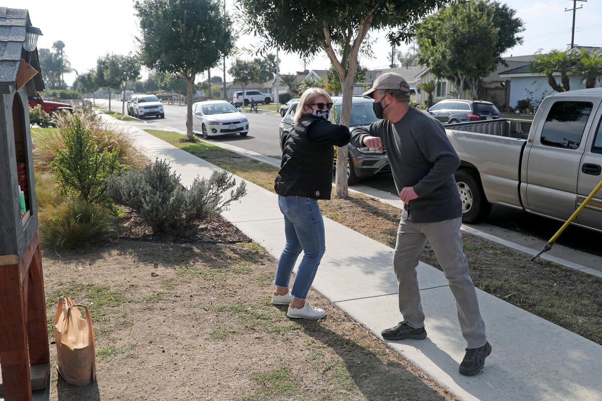 Huntington Beach resident Kristen Hill, left, shares an elbow bump with Malcolm "Mac" Bishop.