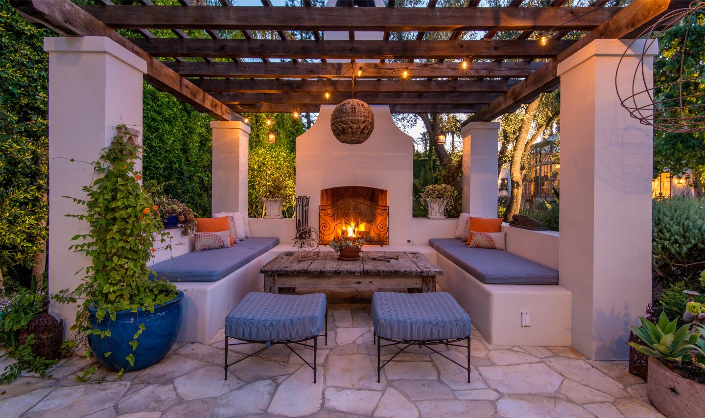 The outdoor fireplace with open slat covering above columns and seating.