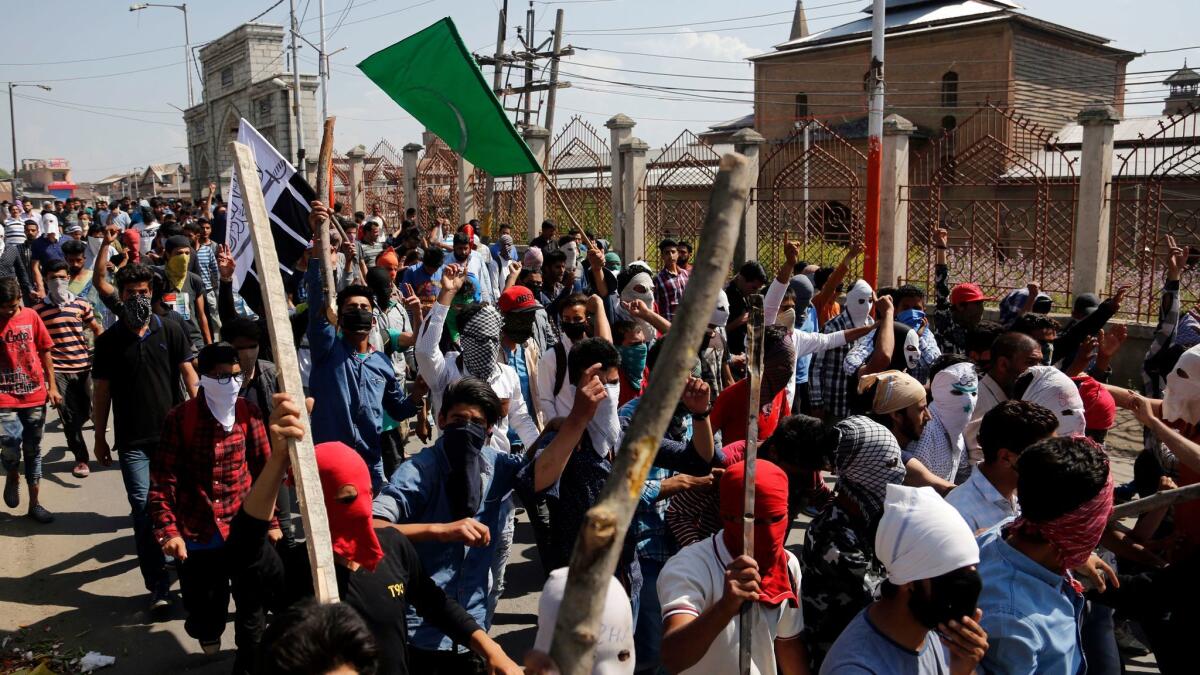 Masked Kashmiri protesters shout freedom slogans and march on a street in Srinagar, India, on May 27, 2017.