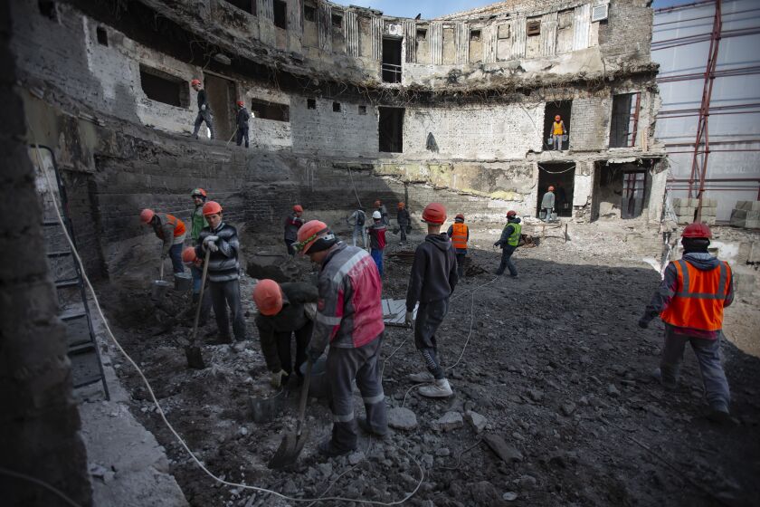 Trabajadores de construcción limpian lo que queda del teatro de Mariúpol para utilizarlo en la construcción de un nuevo teatro, en Mariúpol, en la región de Donetsk, Ucrania, el martes 21 de marzo de 2023. (AP Foto/Alexei Alexandrov)