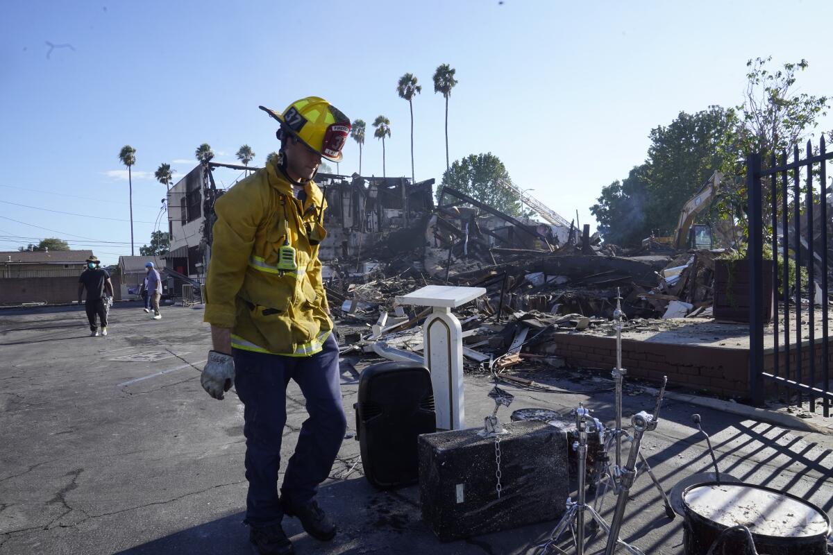 A Los Angeles fireman recovers musicals instruments following a fire at the Victory Baptist Church in Los Angeles, Sunday, Sept. 11, 2022. Authorities say an arson investigation is under way after a fire destroyed the historic church in South Los Angeles. (AP Photo/Damian Dovarganes)
