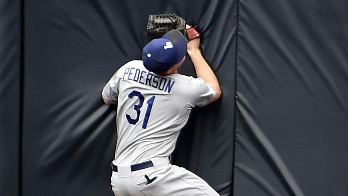 Dodgers center fielder Joc Pederson crashes into the wall moments after making an over-the-shoulder catch on the run on a ball hit by Padres outfielder Justin Upton in the ninth inning Sunday.