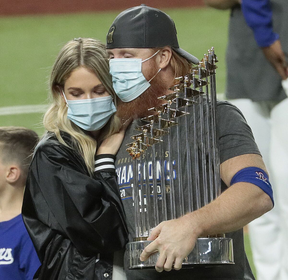 Justin Turner hugs his wife and holds the Commissioner's Trophy.